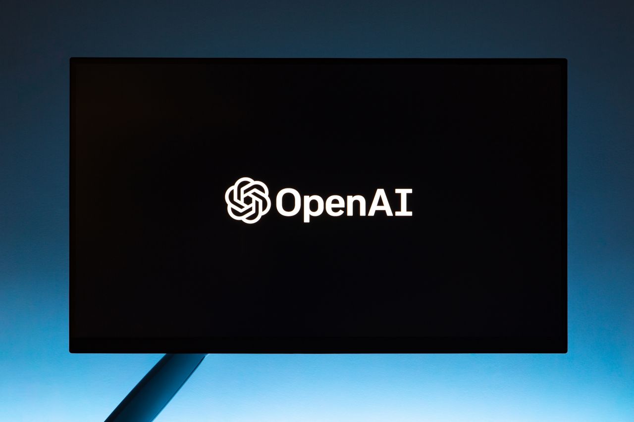 team-03 Minimalist display of OpenAI logo on a screen, set against a gradient blue background.